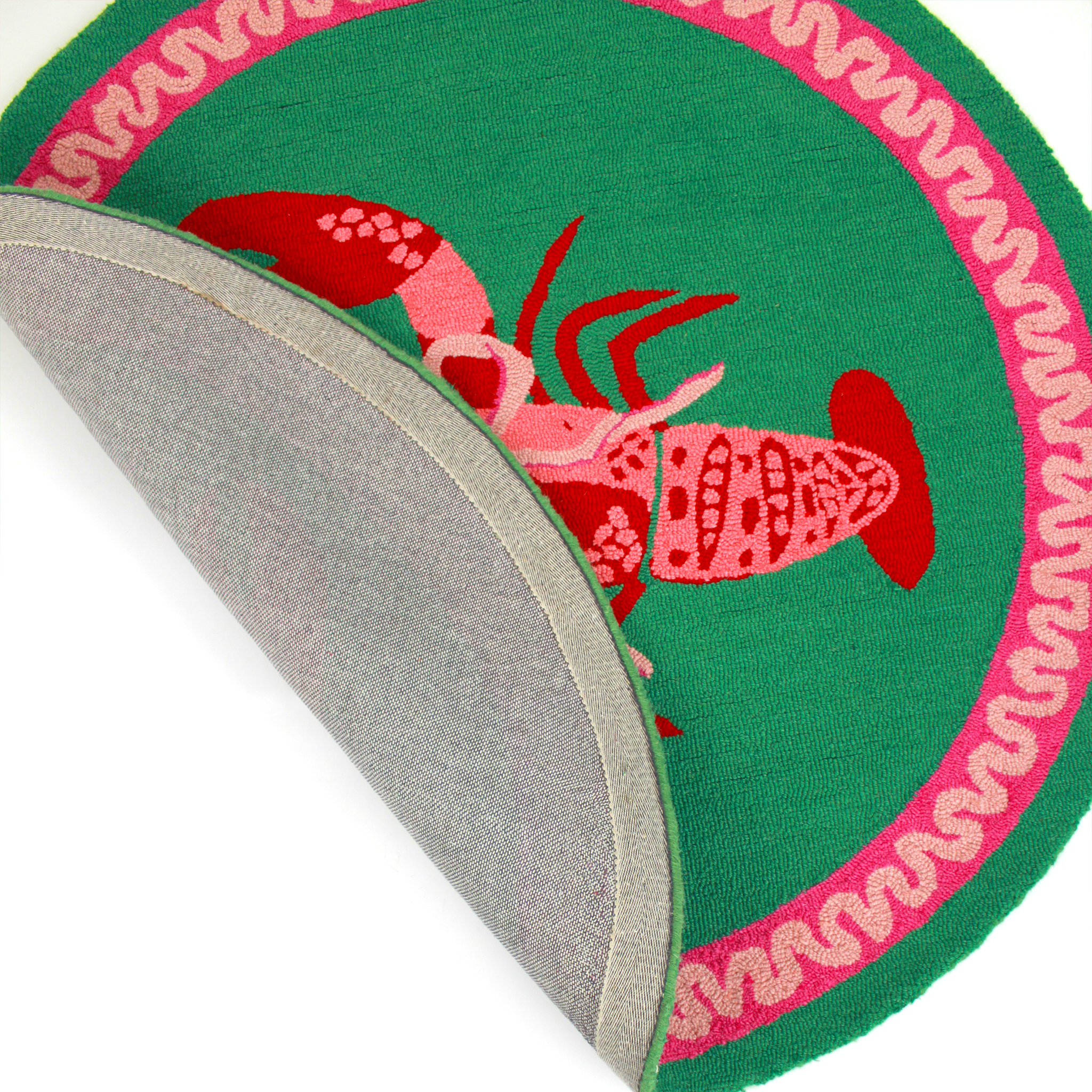 close up details of a round green and pink rug with a central red and pink lobster motif.