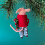 back of a felt mouse ornament wearing a red jacket and patterned blue-green pants, holding a festive green wreath with red accents.