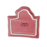 a reverse side of a pink christmas accent plate in the shape of a christmas gift. 