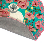 close up of a  pink and green floral rug featuring a scalloped border and large central pug motif