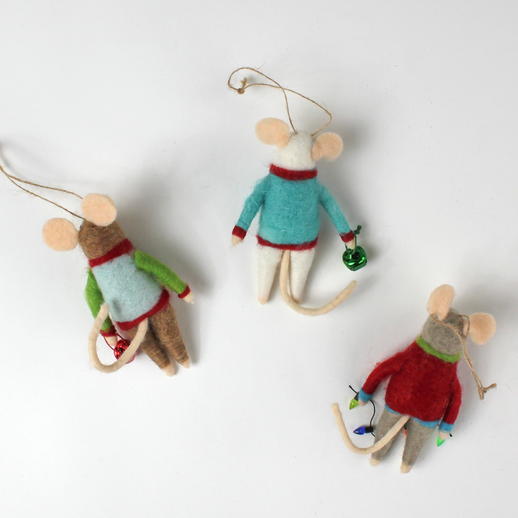 back of the Three felt mouse ornaments dressed in colorful holiday sweaters—one with a snowman, one with a wreath, and one with a Christmas tree—each holding a gift.
