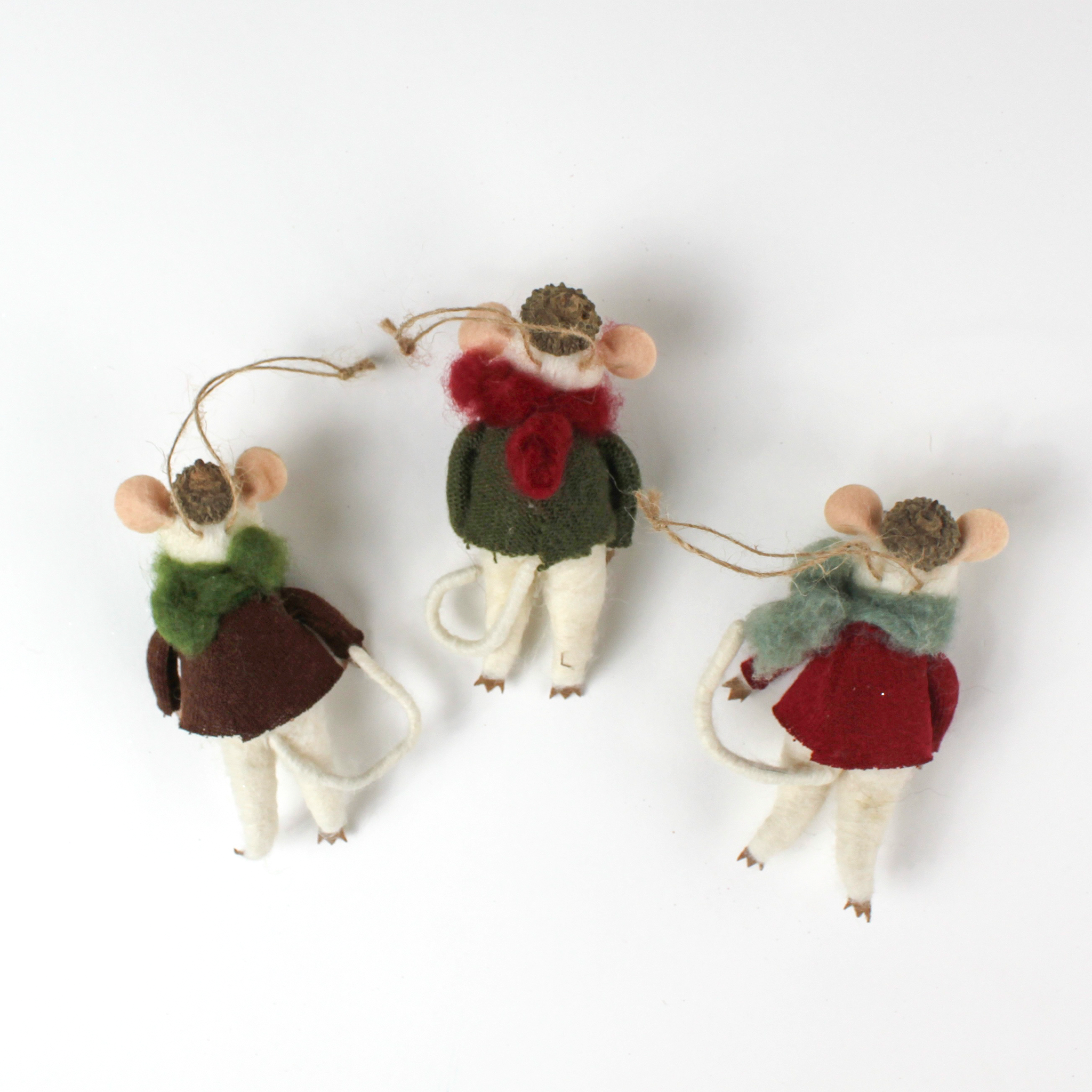 back of the Three felt mouse ornaments wearing cozy sweaters with festive designs—a snowman, a tree, and a snowflake—each topped with a tiny acorn cap and ready to hang.
