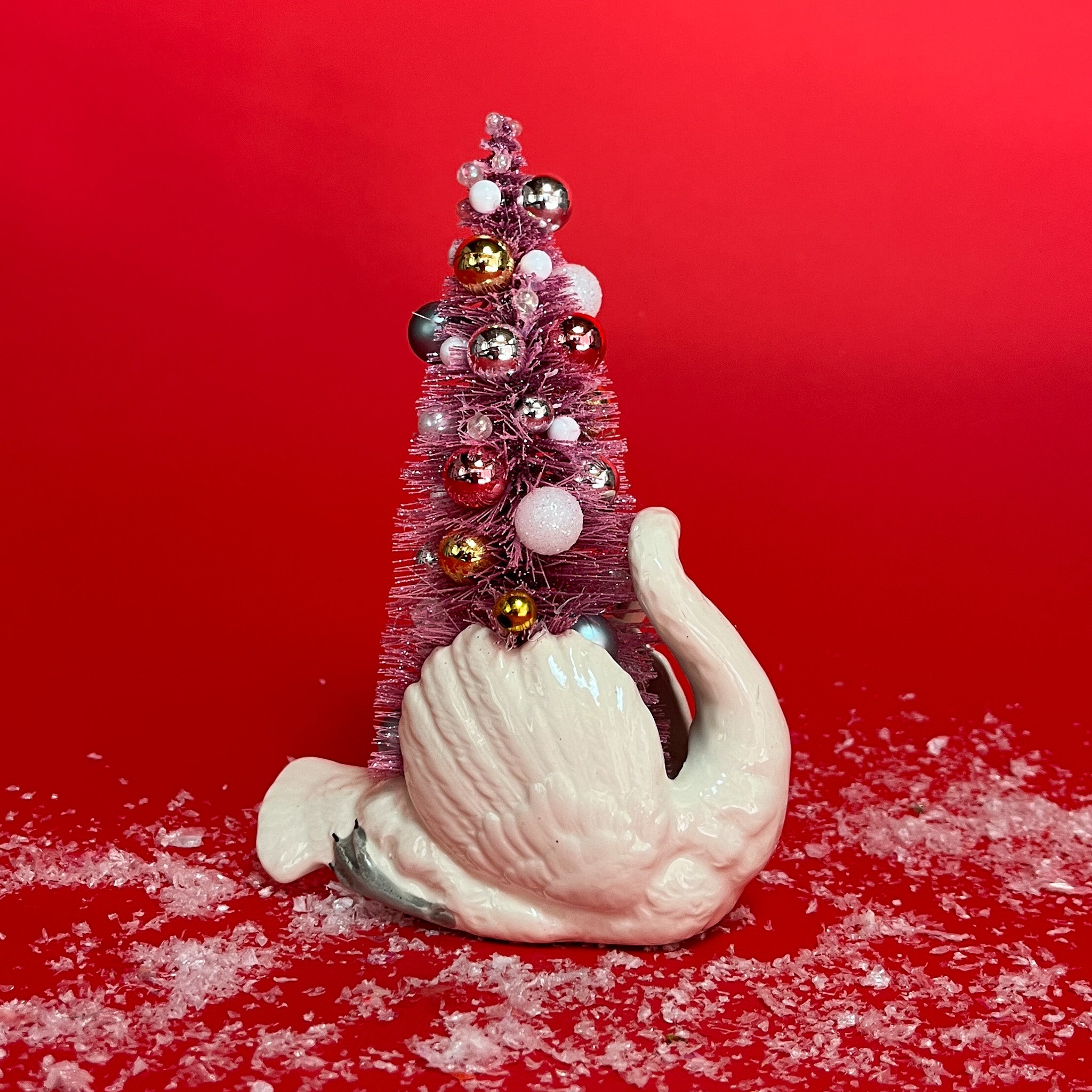 back of a White Vintage Arched-Neck Ceramic Swan w/Pink Glitter Christmas Tree Centerpiece against a red background. 