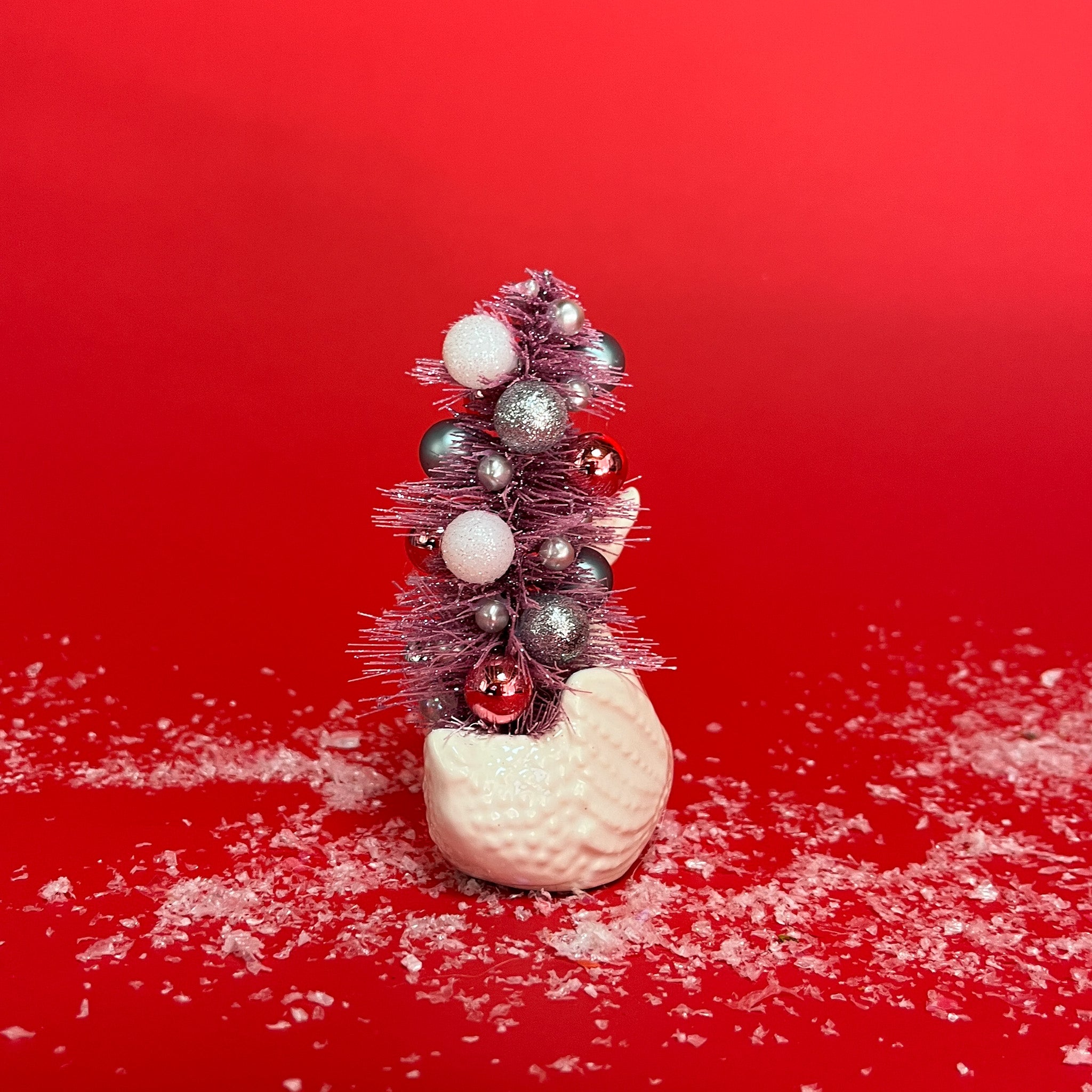 back of a Vintage Small White Ceramic Swan w/ Pink Glitter Christmas Tree Centerpiece against a red background. 