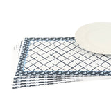 a set of blue and white floral paper placemats lying on a white surface with a white plate on top