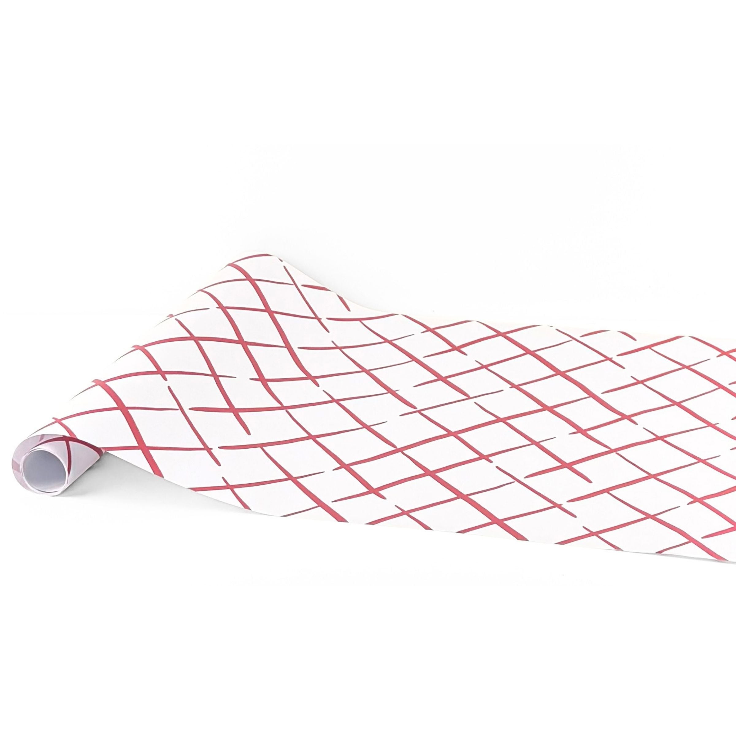 A white paper table runner with intersecting pink and red crosshatch lines in a modern geometric pattern.