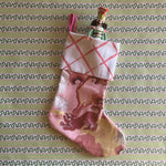 a pink christmas stocking with a pink and white lattice design cuff and a pink and yellow chinoiserie pattern stocking. 