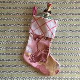 a pink christmas stocking with a pink and white lattice design cuff and a pink and yellow chinoiserie pattern stocking. 