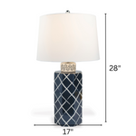 A navy  table lamp with a navy blue porcelain base featuring a white lattice pattern and a plain white lampshade with arrows denoting dimensions 28" high and 17" wide