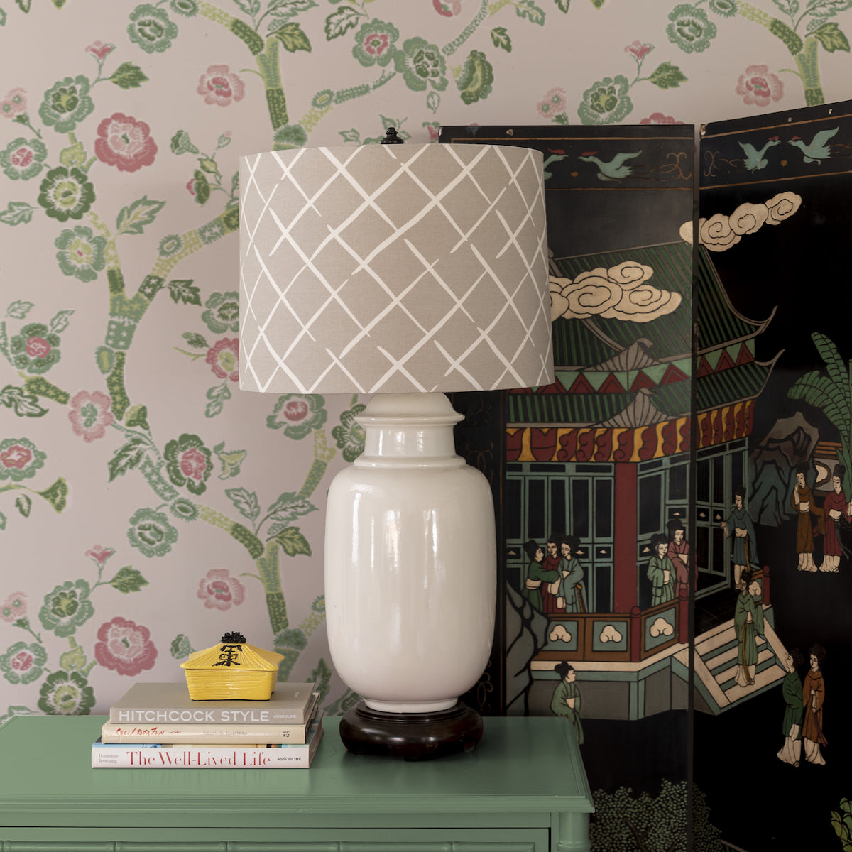 a beige lamp and oriental screen against a wall of pale pink chinoiserie wallpaper