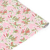 Elegant botanical gift wrap featuring lush green foliage, coral floral accents, and soft pink backgrounds.