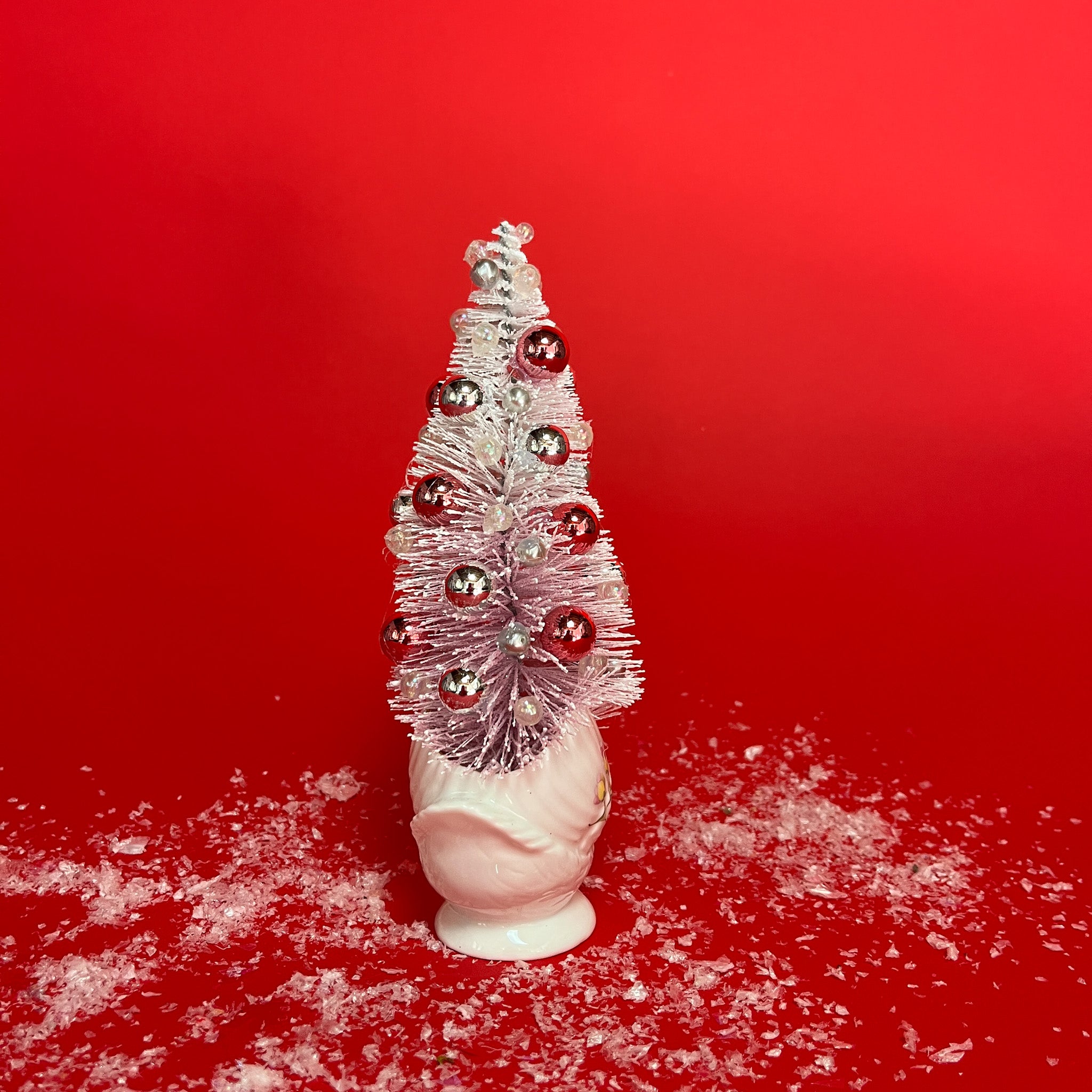 back of a white floral Vintage Ceramic Swan w/ Flocked Christmas Tree Centerpiece against a red background. 