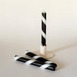 Three black-and-white taper candles on a light background, one standing upright and two lying horizontally.