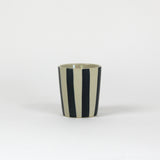 Ablack striped ceramic cup in on a white background. 