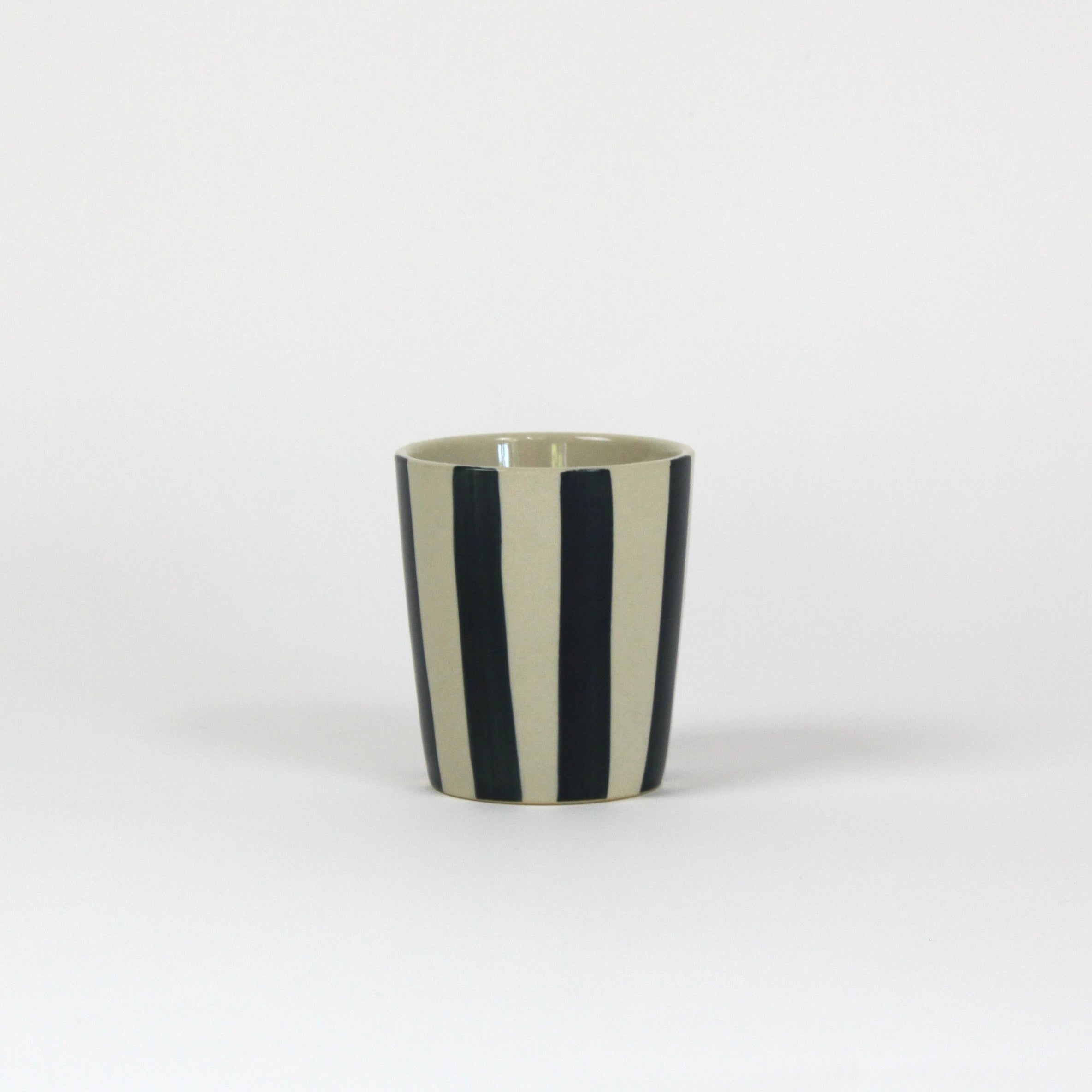 Ablack striped ceramic cup in on a white background. 