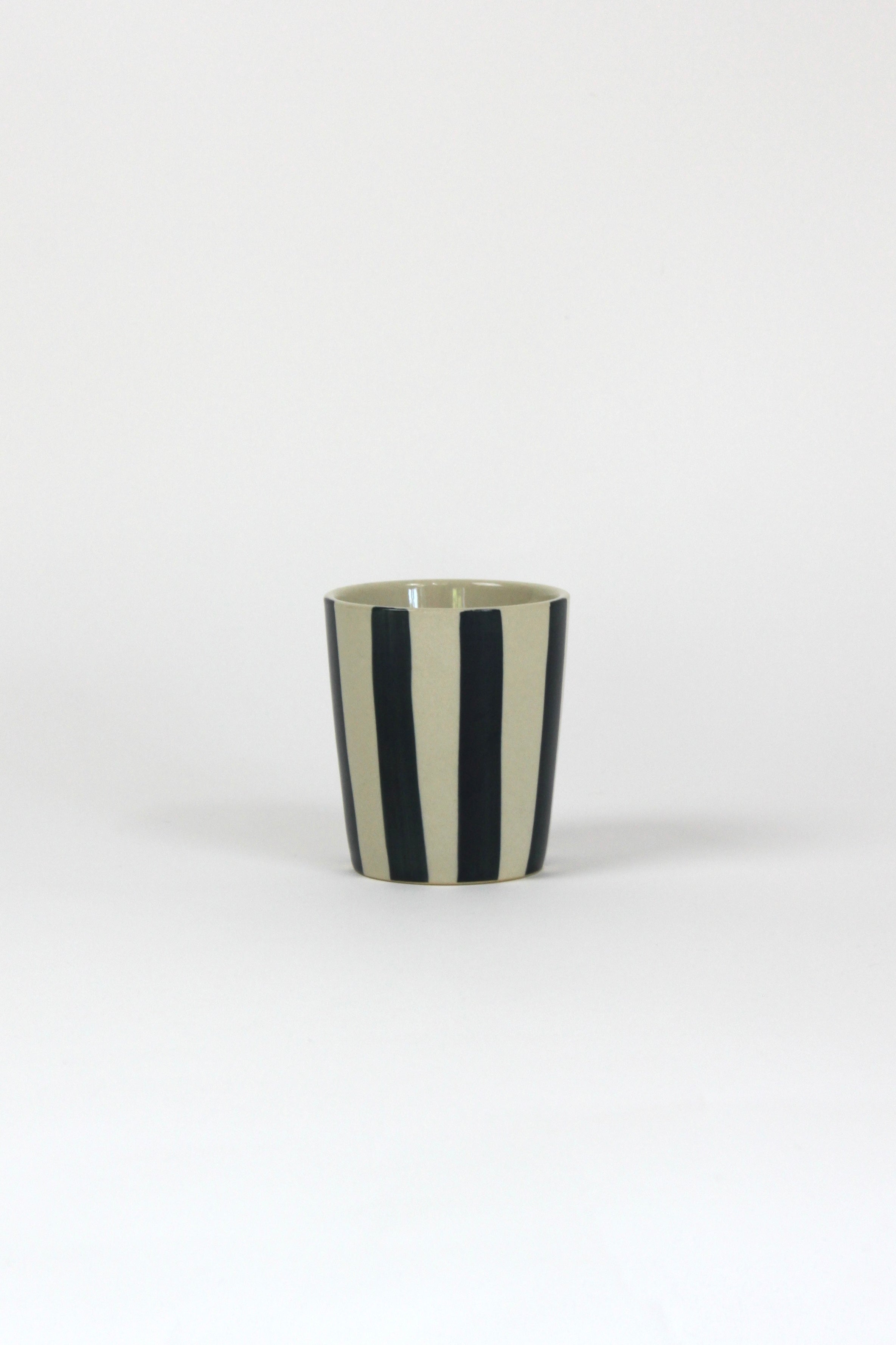 Ablack striped ceramic cup in on a white background. 