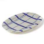 Oval ceramic blue and white platter painted with a blue check pattern on a white background