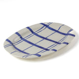 Oval ceramic blue and white platter painted with a blue check pattern on a white background