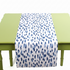 a blue and white brushtroke patterned paper table runner on a green table. 