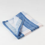 Close-up of folded blue and white striped cloth napkins with red scalloped trim.