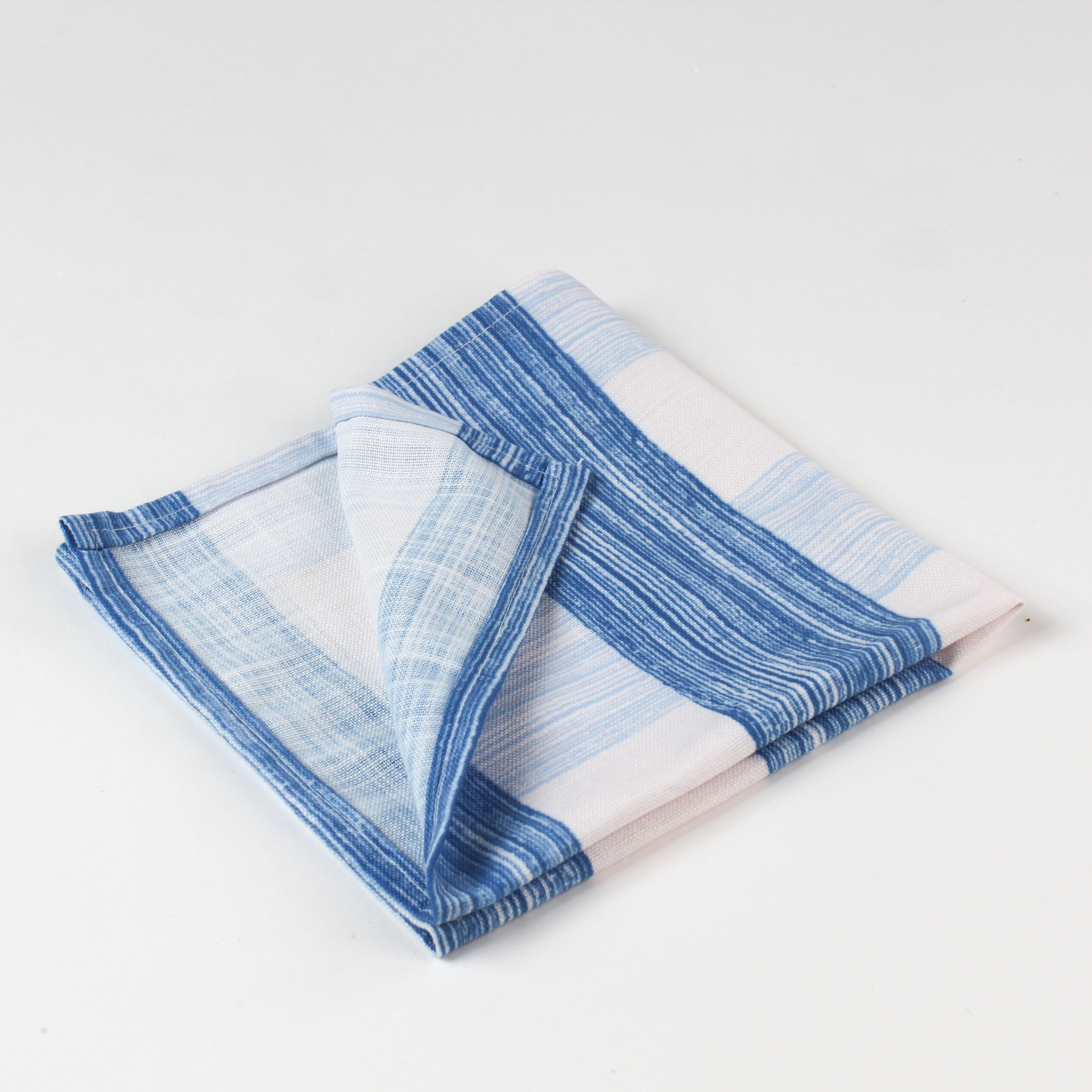 Close-up of folded blue and white striped cloth napkins with red scalloped trim.