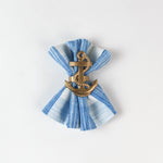 Blue and white striped cloth napkin styled with a gold anchor napkin ring.