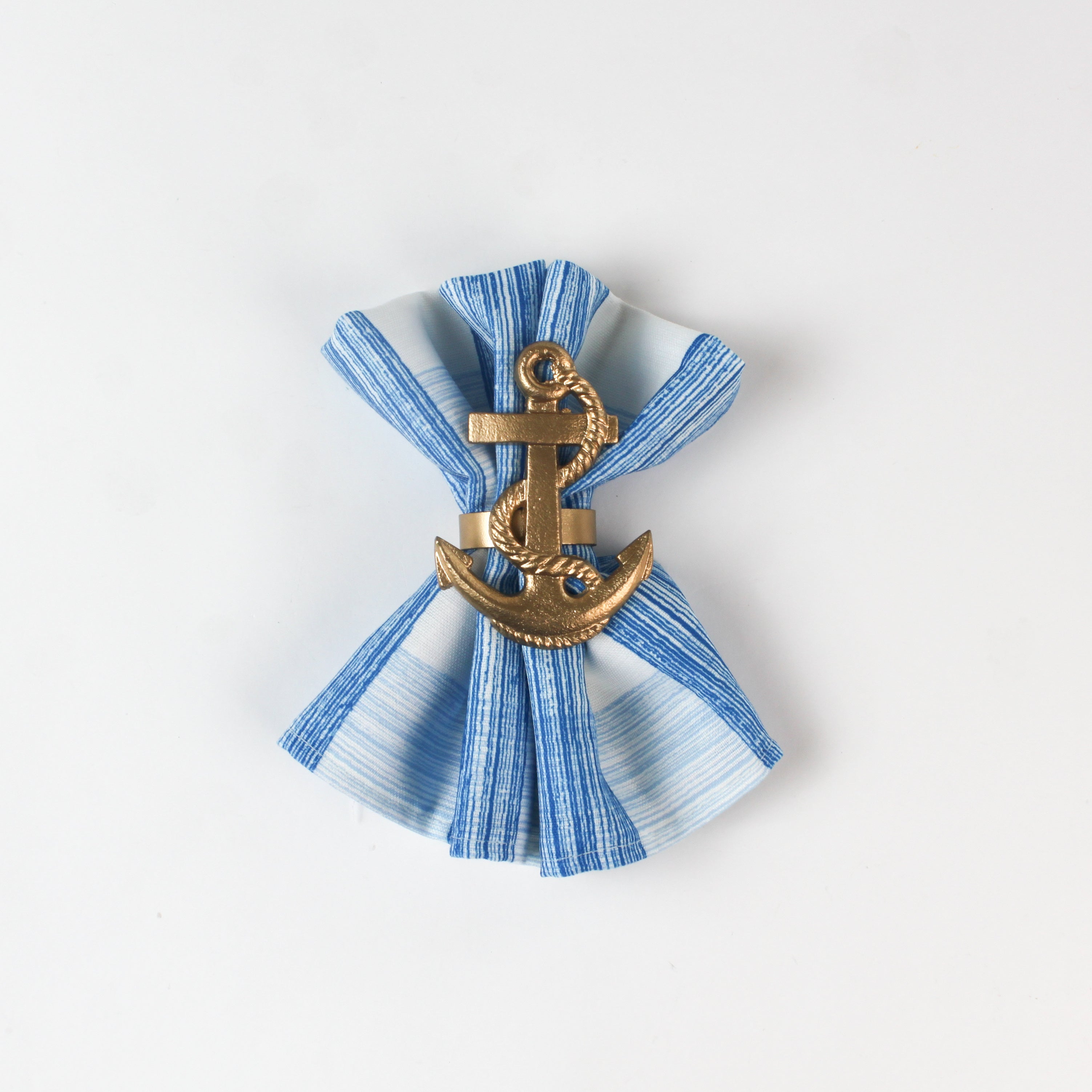Blue and white striped cloth napkin styled with a gold anchor napkin ring.