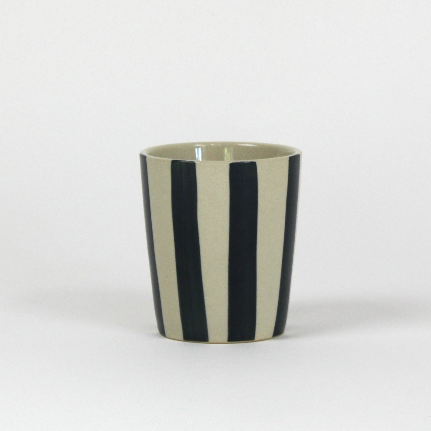 A blue striped ceramic cup in on a white background. 