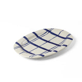 Oval ceramic serving platter with hand-painted blue plaid pattern on a white background viewed at an angled side perspective.