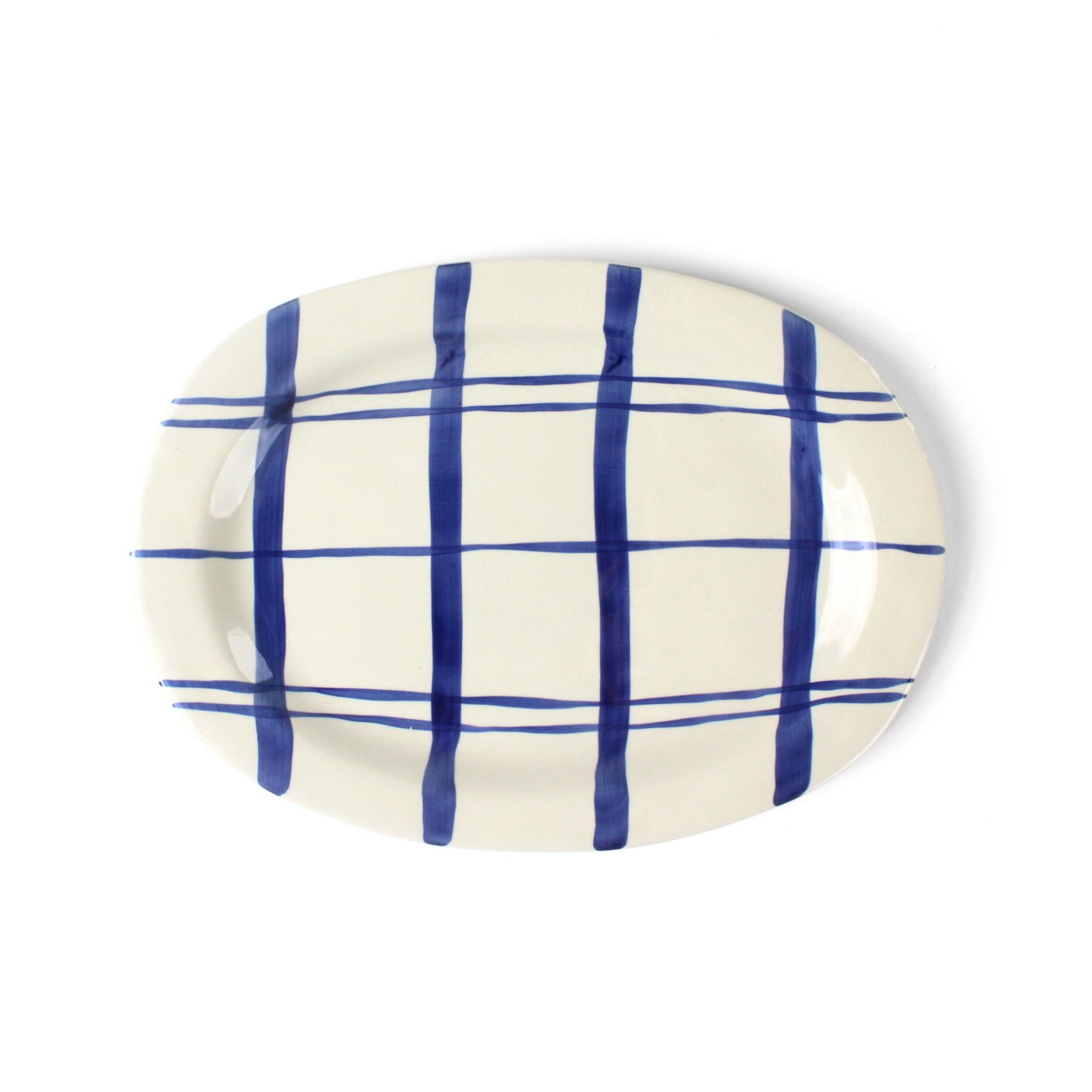 Oval ceramic blue and white platter painted with a blue check pattern on a white background