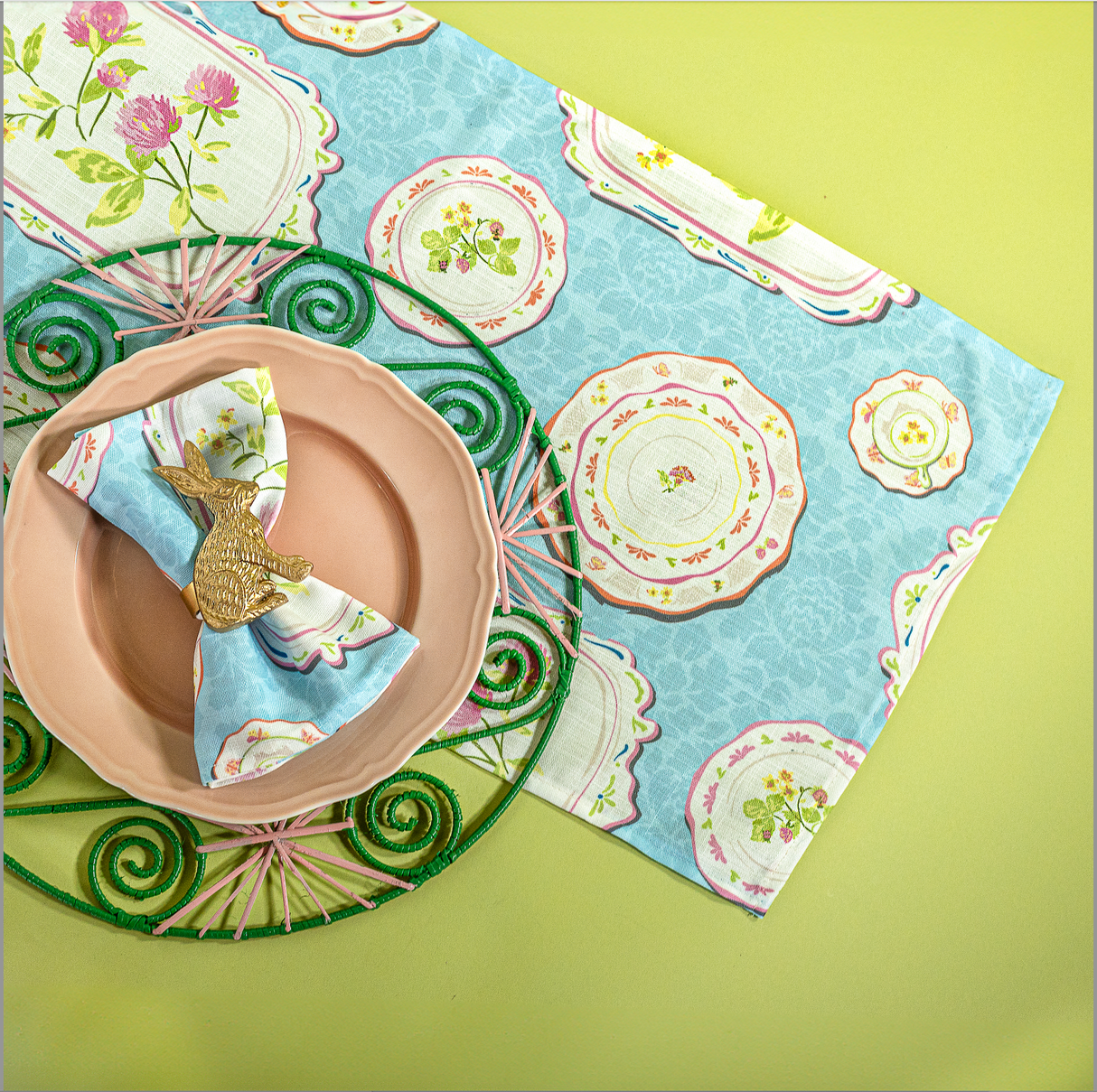 A blue vintage plates fabric table runner with a pink plate on top. 