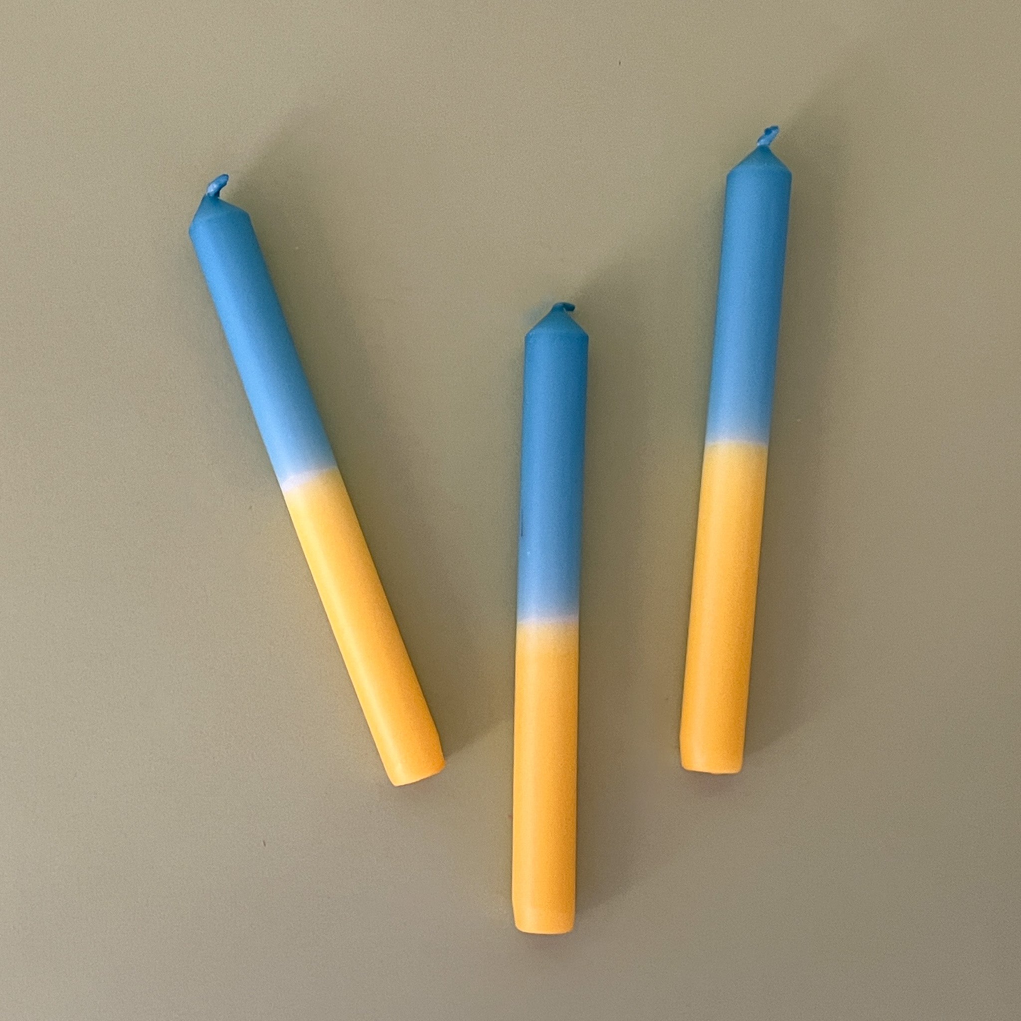 a pair of yellow and blue taper candles