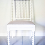 A white bobbin chair without arms.