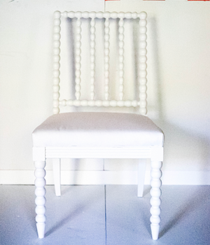 A white bobbin chair without arms.