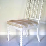 a white bobbin chair with a beige plaid seat.