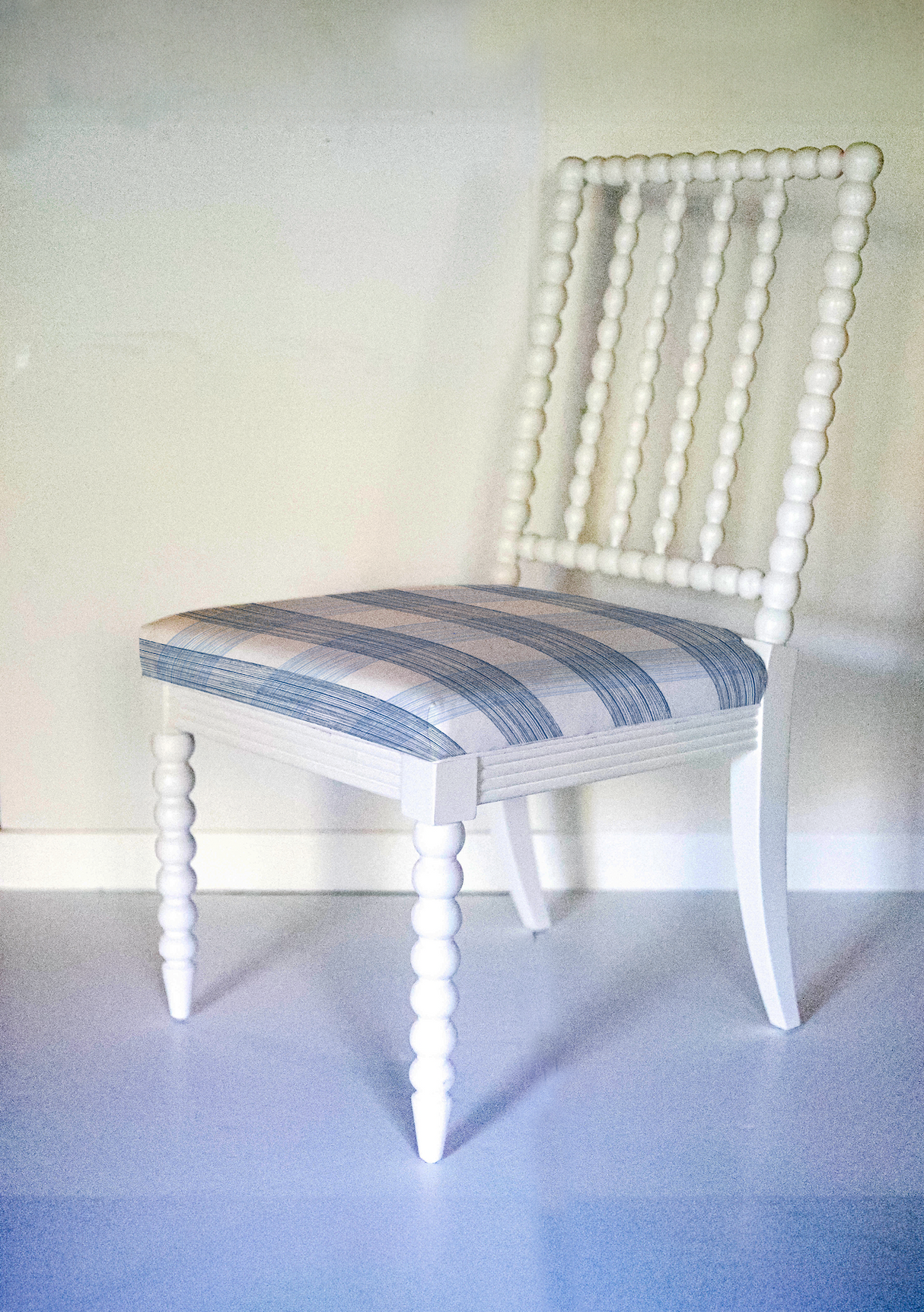 A white bobbin chair with a blue plaid seat