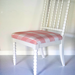 A white bobbin chair with a red plaid seat.