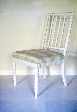 A white bobbin chair with a green plaid seat. 