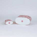 Two cylindrical christmas caddies with pink nutcracker patterns on a light gray background