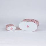 Two cylindrical christmas caddies with pink nutcracker patterns on a light gray background