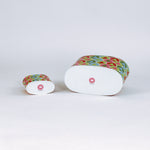Two christmas casdies with colorful tree pattern lying on their sides on a white background