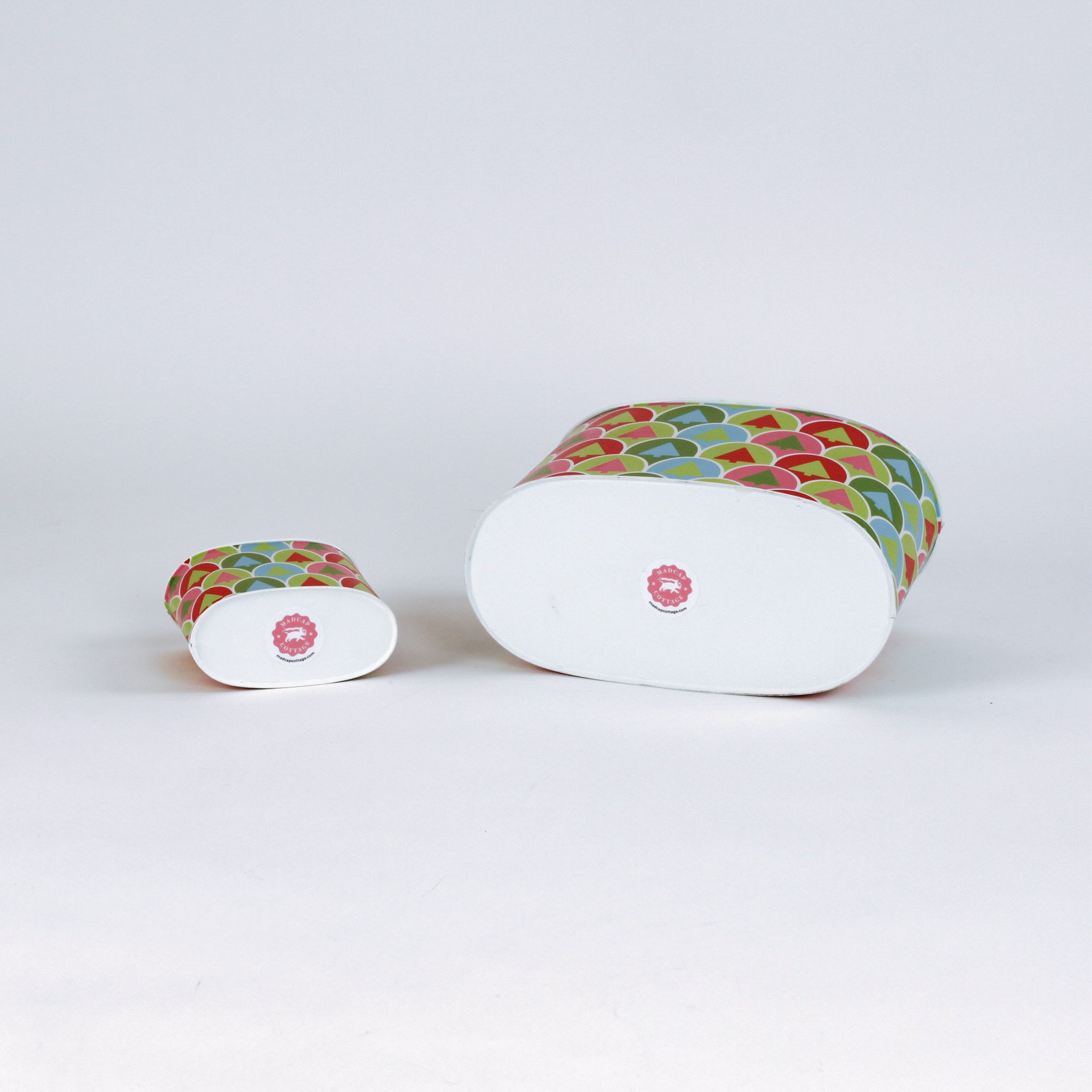 Two christmas casdies with colorful tree pattern lying on their sides on a white background