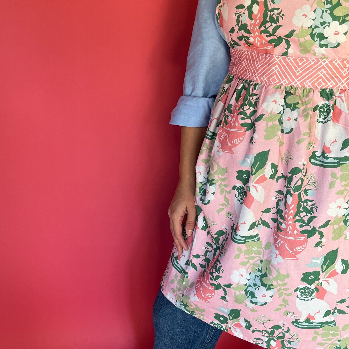 a woman wearing a pink and green chinoiserie apron featuring the Imperial Palace pattern from madcap cottage