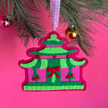 pink felt chinoiserie christmas ornaments in the shape of pagodas against a red background 