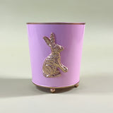 a pink tole cachepot with a gold bunny motif and gold rim and feet.