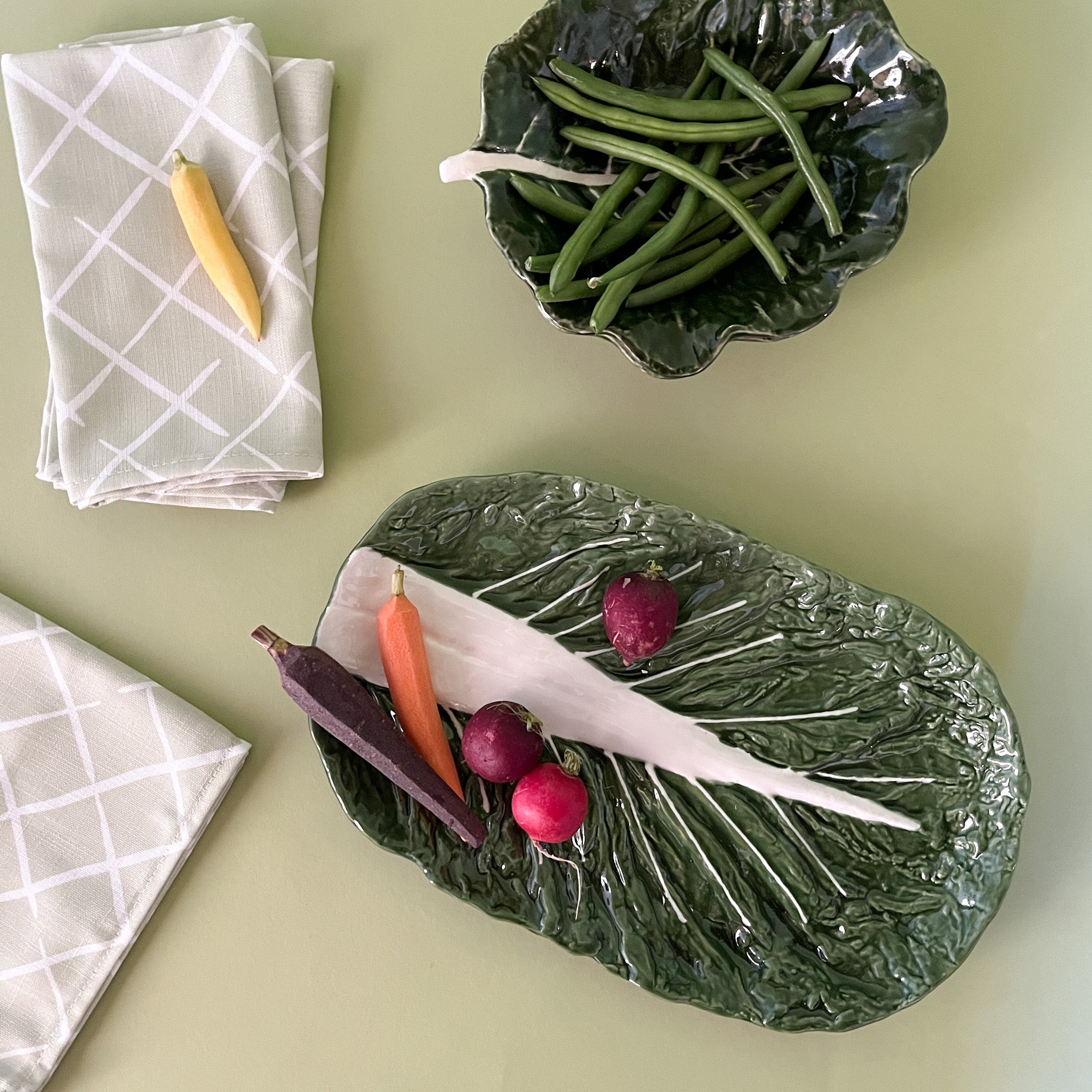 a large ceramic cabbage serving platter with vegetables on it by madcap cottage