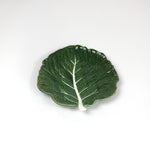 a ceramic green cabbage leaf plate on a white background.