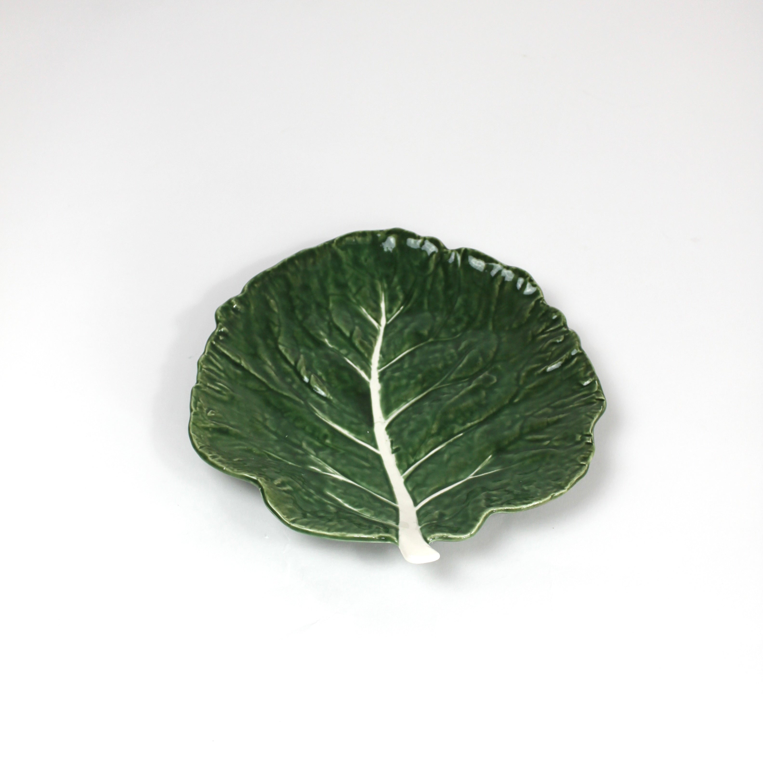 a ceramic green cabbage leaf plate on a white background.