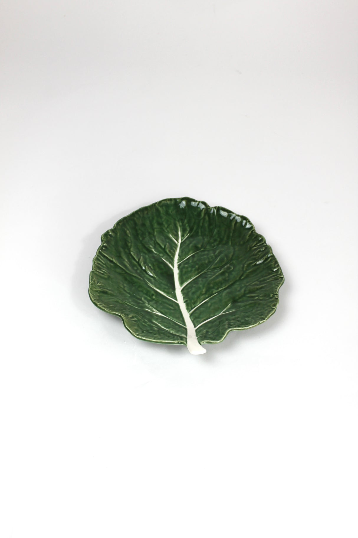a ceramic green cabbage leaf plate on a white background.