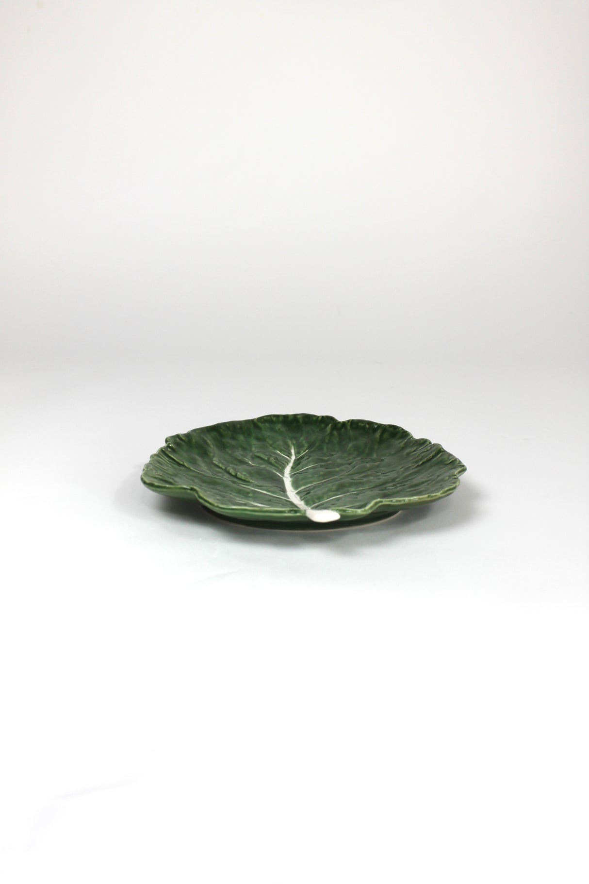 a ceramic green cabbage leaf plate on a white background.
